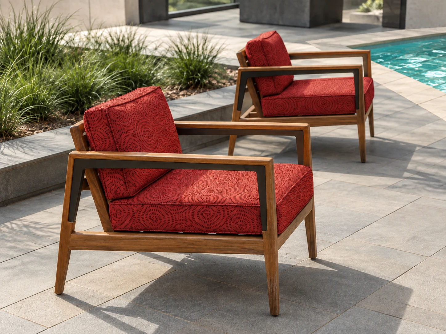 Wooden armchairs upholstered in Solara Basket Red on a sunlit patio with a subtle glimpse of swimming pool water nearby