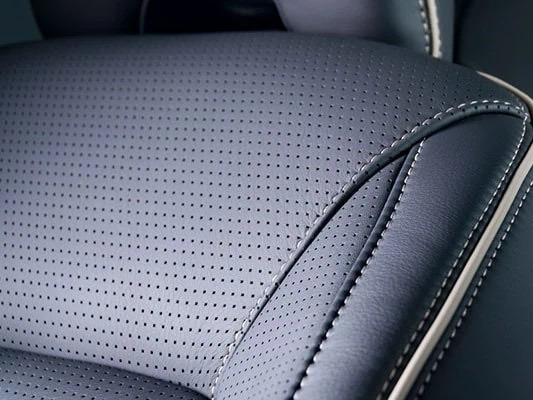 Detailed dark perforated automotive upholstery with stitching and piping